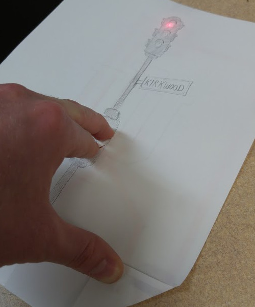 Alexander's hand completes the circuit: the drawing of a traffic light is illuminated red because of a red LED.